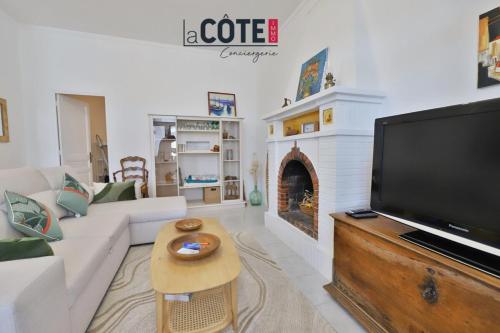een woonkamer met een bank, een tv en een open haard bij L'Oursinade in Carry-le-Rouet