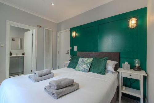 a bedroom with a large bed with a green headboard at The Southport Seaside Snug Suites in Southport