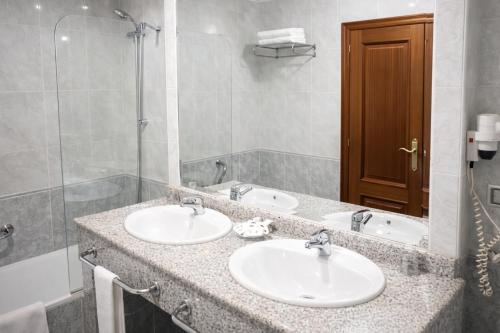 a bathroom with two sinks and a shower at Motel Punta Cana in Santiago de Compostela