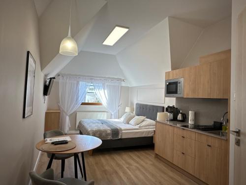 a bedroom with a bed and a table and a kitchen at Willa Perełka in Kudowa-Zdrój