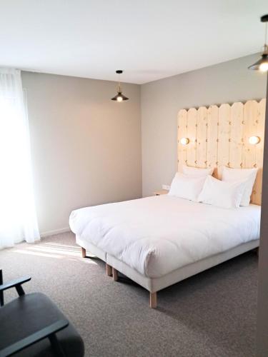 a bedroom with a large white bed with a headboard at Hôtel du Cheval Blanc Brunstatt in Brunstatt