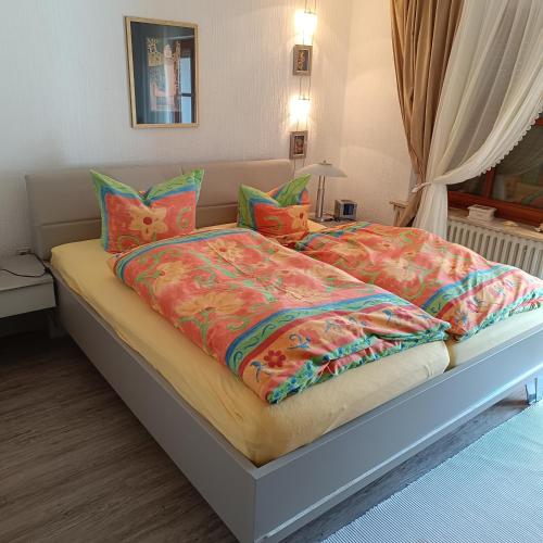 a bed with colorful blankets and pillows on it at Ferienwohnung Röder am Schwimmteich in Bischofsheim an der Rhön