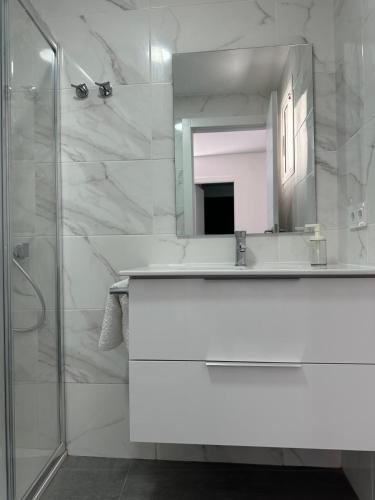 a white bathroom with a sink and a mirror at Ático Rocamar in La Restinga