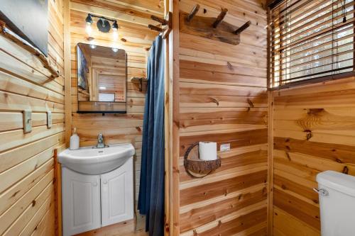 a bathroom with wooden walls and a sink and a toilet at Bison Trail House- Rustic Cabin Retreat in Rapid City