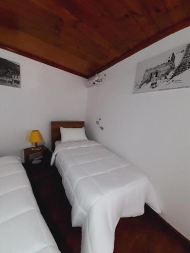 two beds in a room with white sheets at Edward Lear - Heritage Guest House in Berat