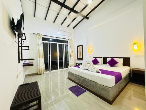 a bedroom with a large bed with purple pillows at Heriance Anuradhapura in Tammannewa