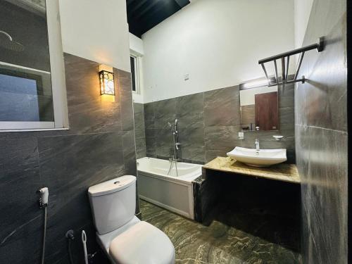 a bathroom with a toilet and a sink and a tub at Heriance Anuradhapura in Tammannewa