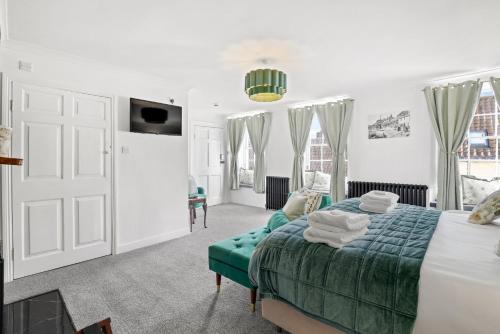 a white bedroom with a bed and a green couch at The Drawing Room at The Merchants in Berwick-Upon-Tweed