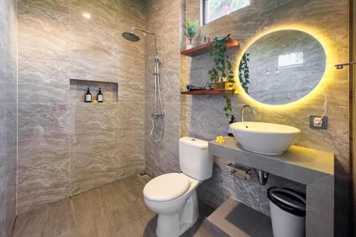 a bathroom with a toilet and a sink and a mirror at Damara Ubud in Ubud