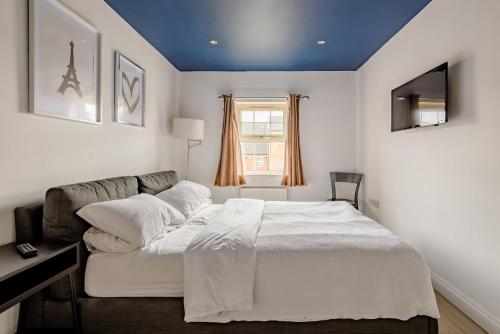 a bedroom with a large bed with a blue ceiling at Main House in Rotherham