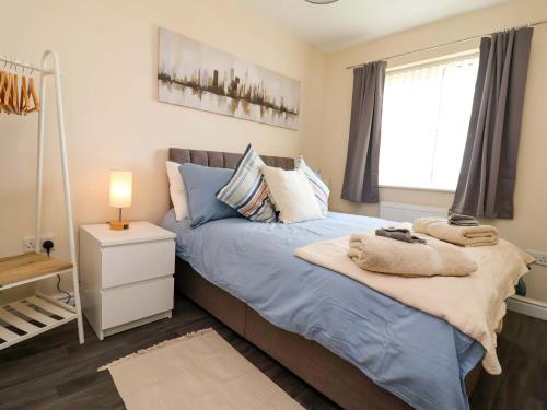 a bedroom with a blue bed and a window at The Beach Escape in Prestatyn