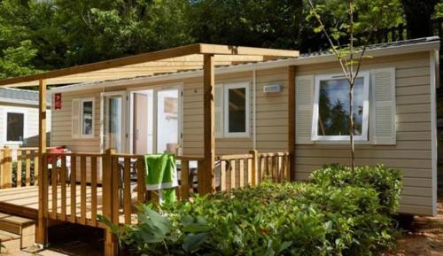 a small house with a porch and a wooden deck at Camping le Lizot - Mobil home 3 pièces 4/6 personnes + TV MAE-8684 in Saint-Mandé-sur-Brédoire