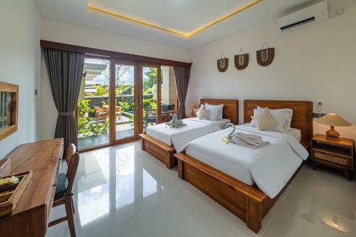 a bedroom with two beds and a desk at Damara Ubud in Ubud