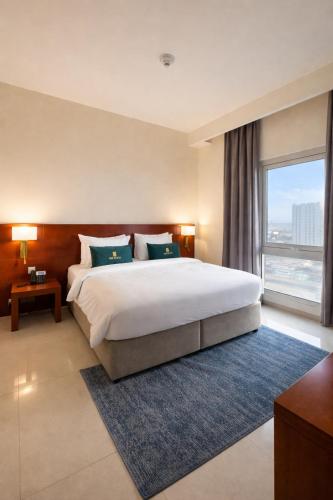a bedroom with a large bed and a large window at Acacia Hotel Ras Al Khaimah by AMR in Ras al Khaimah