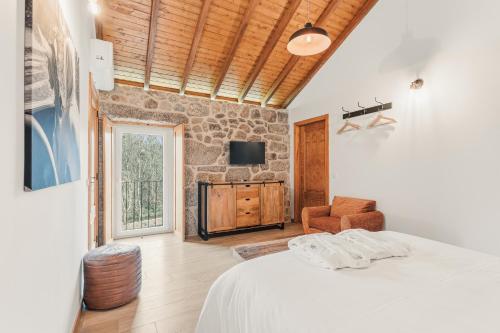 a bedroom with a bed and a stone wall at Banduja Reserve - Slow by nature in Celorico de Basto