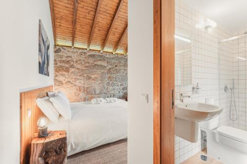 a bedroom with a bed and a bathroom with a sink at Banduja Reserve - Slow by nature in Celorico de Basto