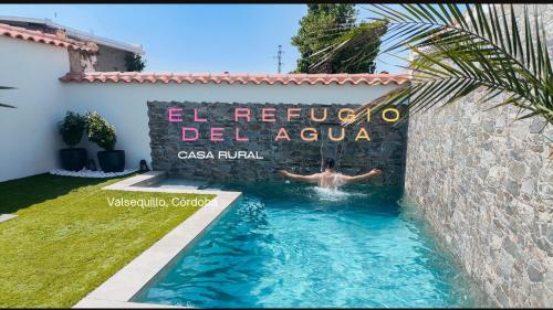 a man swimming in a swimming pool in front of a building at El Refugio del Agua - Casa Rural in Valsequillo