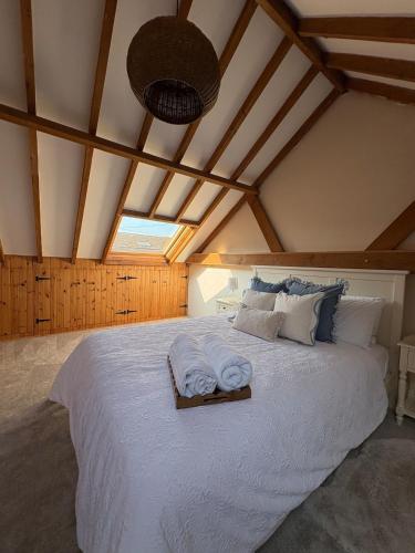 a bedroom with a large white bed with towels on it at Wayeview Cottage on working Devon farm in Ipplepen