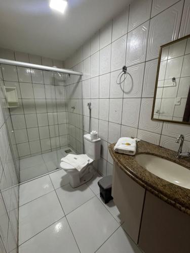 a bathroom with a toilet and a shower and a sink at Pousada Tambaú in São Luís