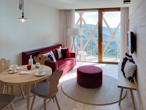 a living room with a red couch and a table at Falkensteiner Residences edelweiss in Katschberghöhe