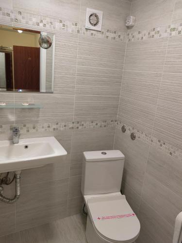 a bathroom with a white toilet and a sink at Пиргуля in General-Toshevo
