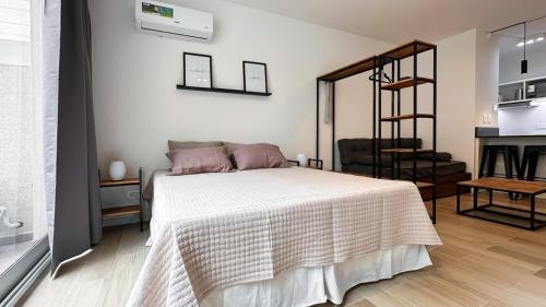 a bedroom with a white bed and a kitchen at Hermoso Studio Premium en Microcentro in Buenos Aires