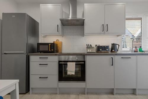 a kitchen with white cabinets and a stove top oven at Urban Heights - 2 Bed Apartment - Short Stays UK Ltd in Exeter