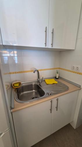 a kitchen with a sink and white cabinets at Primera Linea de playa in Almería