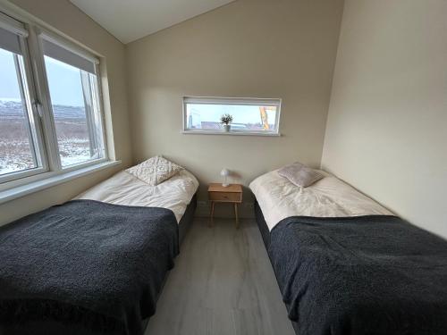 two beds in a room with two windows at Brúarárbyggð B1 in Blaskogabyggo