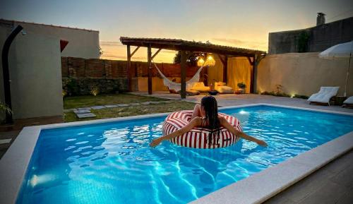 a woman sitting in a chair in a swimming pool at La Casita Nazaré - private pool in Nazaré