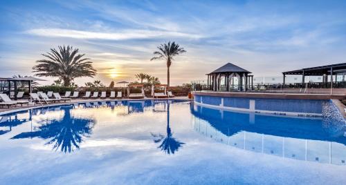 a large swimming pool with chairs and a gazebo at Occidental Jandía Royal Level - Adults Only in Morro del Jable