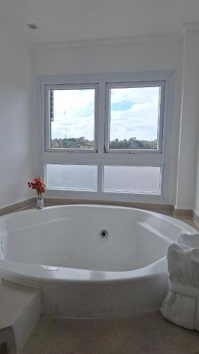 a white bath tub in a bathroom with two windows at Pousada Itália Moderna in Campos do Jordão
