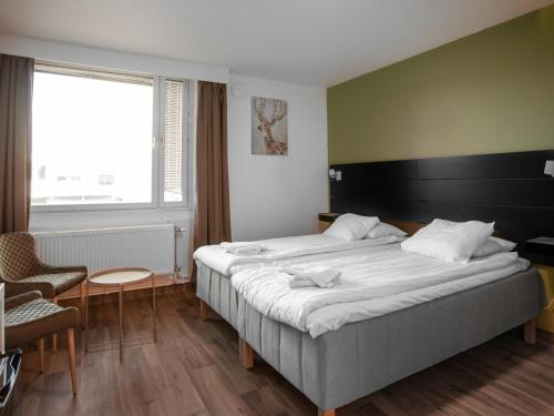 a hotel room with a large bed and a chair at Hotel Aveny in Gävle