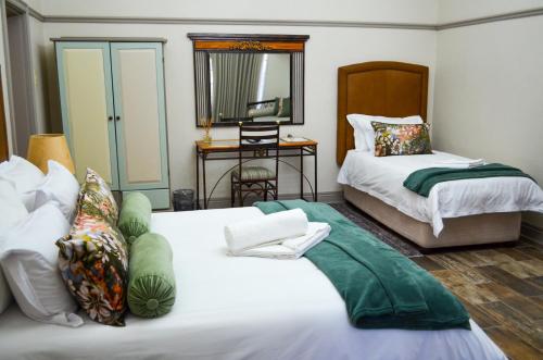 a bedroom with two beds and a mirror at Cecil John Rhodes Guest house in Kimberley