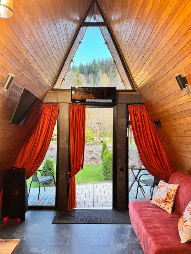 a living room with a large window and a red couch at A-frame-hub з форелевою риболовлею in Slavske