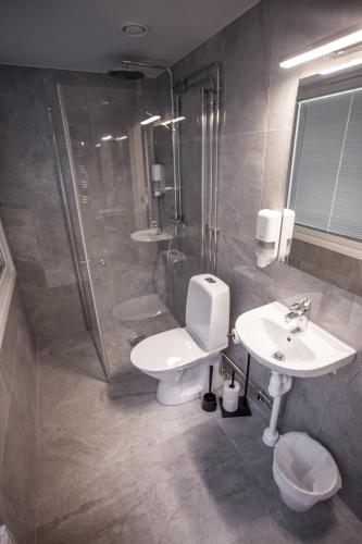 a bathroom with a shower and a toilet and a sink at Hotel Aveny in Gävle