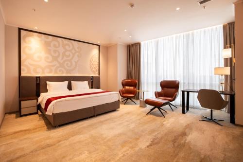 a bedroom with a bed and a table and chairs at ZUMMA Hotel Almaty in Almaty