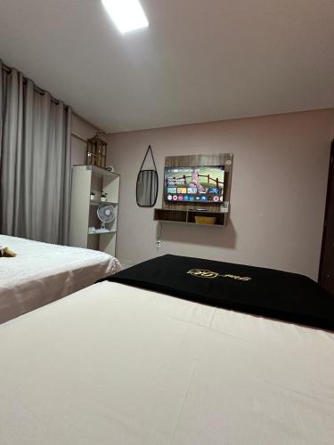 a room with two beds and a tv on the wall at Flat JK 201 in Juazeiro do Norte