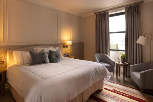 a bedroom with a white bed and a chair and a window at The Lansdowne Kenmare in Kenmare