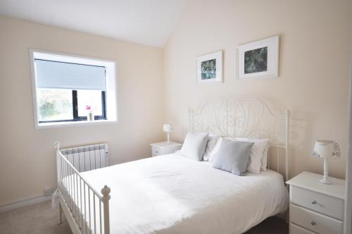 a white bedroom with a white bed and a window at Stable Cottage, Whitebridge Farm in Shaftesbury
