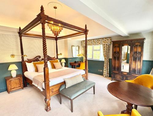 a bedroom with a canopy bed and a table at The Holt Hotel in Steeple Aston