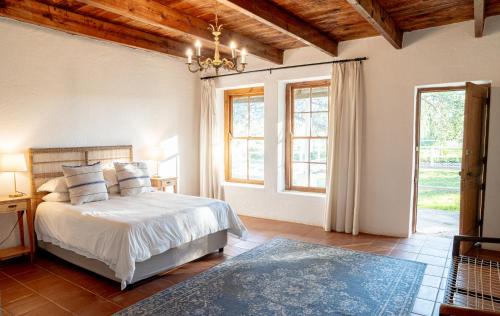 a bedroom with a bed and two windows at Karoo House Collection - Riverdene Lodge in Nieu-Bethesda
