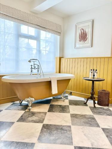 a bath tub in a bathroom with a checkered floor at The Holt Hotel in Steeple Aston