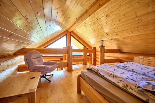 a bedroom with a bed and a chair in a cabin at Golden Log House in Hajdúszoboszló