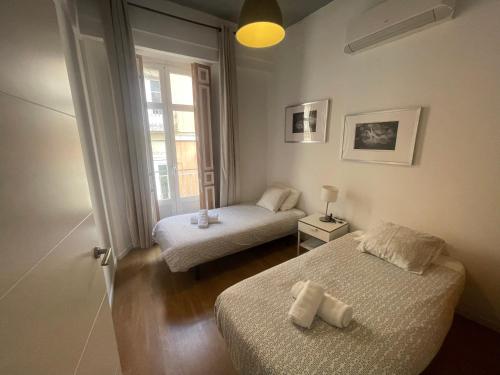 a small room with two beds and a window at Catedral Larios Centro in Málaga