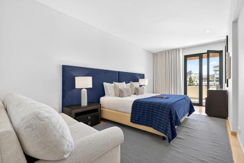 a bedroom with a king sized bed and a couch at Aquamar Pro 116 in Quarteira