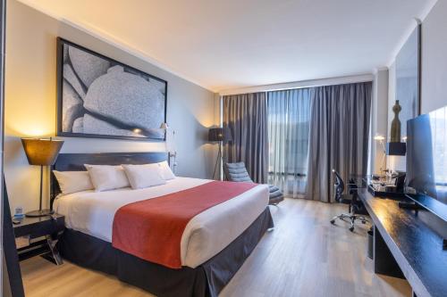 a hotel room with a large bed and a television at Wyndham Santiago Pettra in Santiago