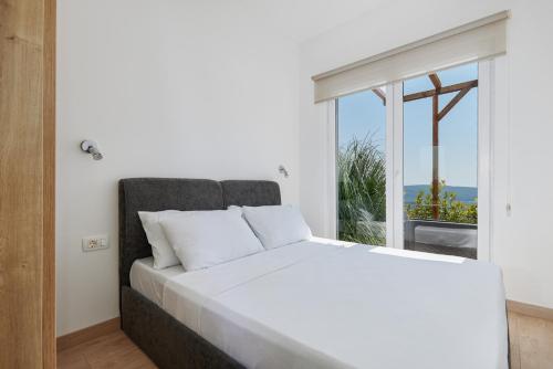 a bedroom with a white bed and a large window at Adriatic Heights Holiday Apartments in Kavač