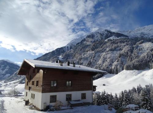 a house in the snow with mountains in the background at Bamerhof in Mittersill