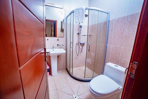 un bagno con doccia, WC e lavandino di LOUMIA Residency a Douala